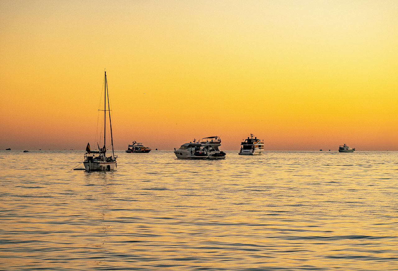 Yachts on water against a yellow sky